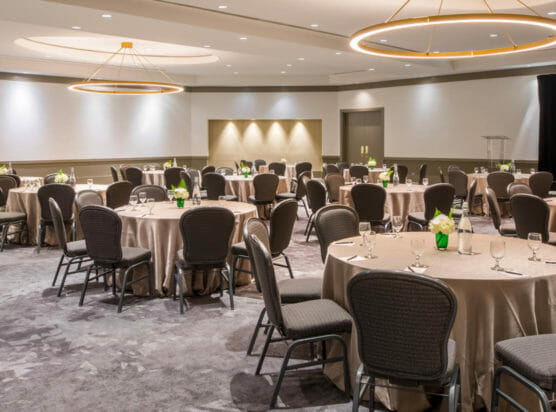 Jordan ballroom with large round tables, screen for presentations, and podium for spreaches