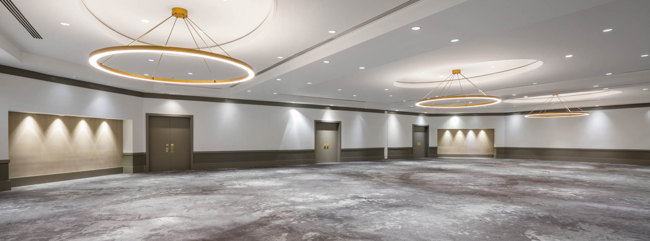 Empty Jordan ballroom with circular chandeliers and gray carpeted floor