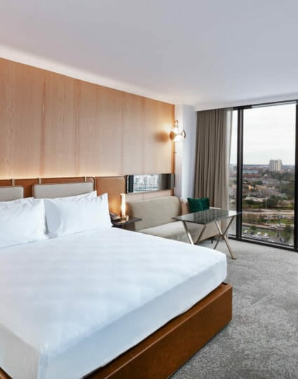 King sized bed room with seating area that includes view of Houston through floor to ceiling windows.