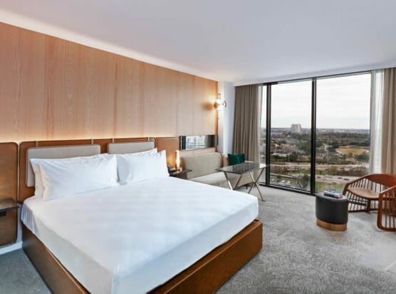 King sized bed room with seating area that includes view of Houston through floor to ceiling windows.