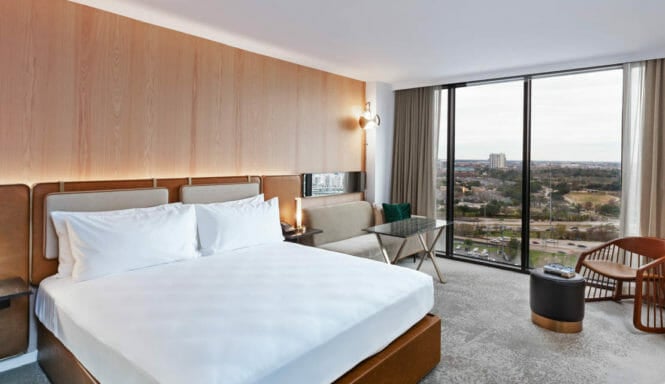 King sized bed room with seating area that includes view of Houston through floor to ceiling windows.