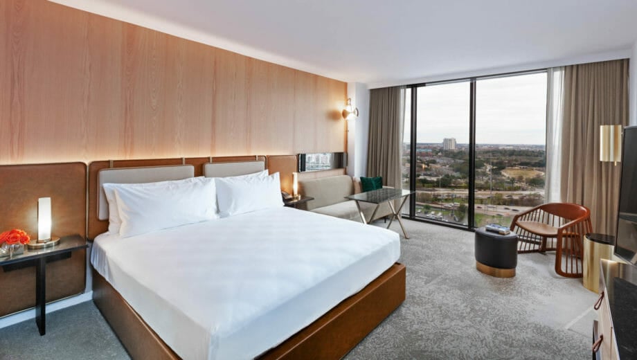 King bedroom with seating area that has view of Houston through floor to ceiling windows