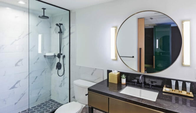 Bathroom with stand up shower, toilet, and vanity with circular mirror