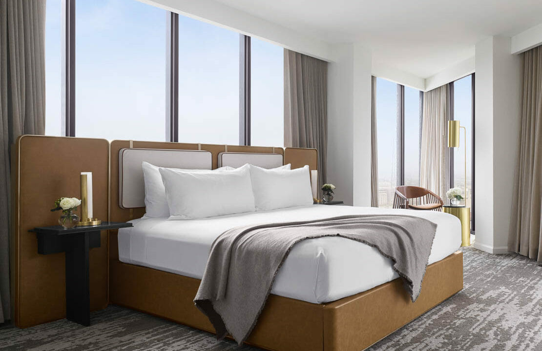 Luxurious king sized bed surrounded by floor to ceiling windows in the Presidential Suite