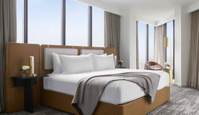 Luxurious king sized bed surrounded by floor to ceiling windows in the Presidential Suite
