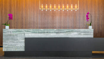 The concierge desk at C Baldwin hotel has pink flowers at each end