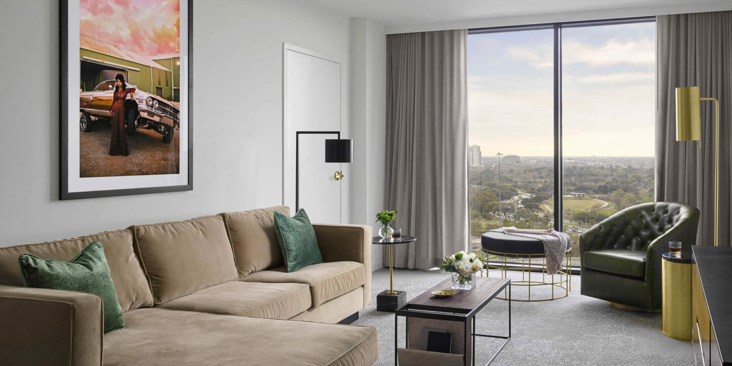 Suite living room area with tan sectional and lounge chair with modern lighting fixtures and coffee table
