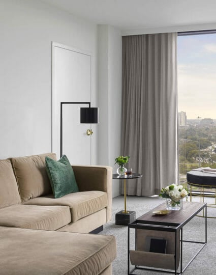 Suite living room area with tan sectional and lounge chair with modern lighting fixtures and coffee table