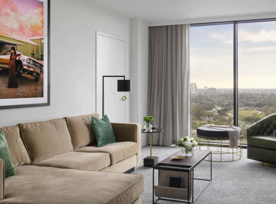 Suite living room area with tan sectional and lounge chair with modern lighting fixtures and coffee table