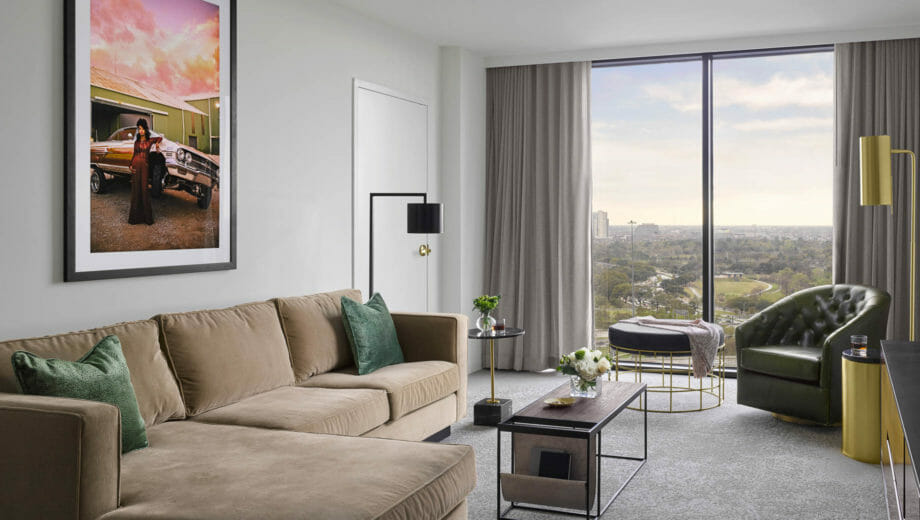 Suite living room area with tan sectional and lounge chair with modern lighting fixtures and coffee table