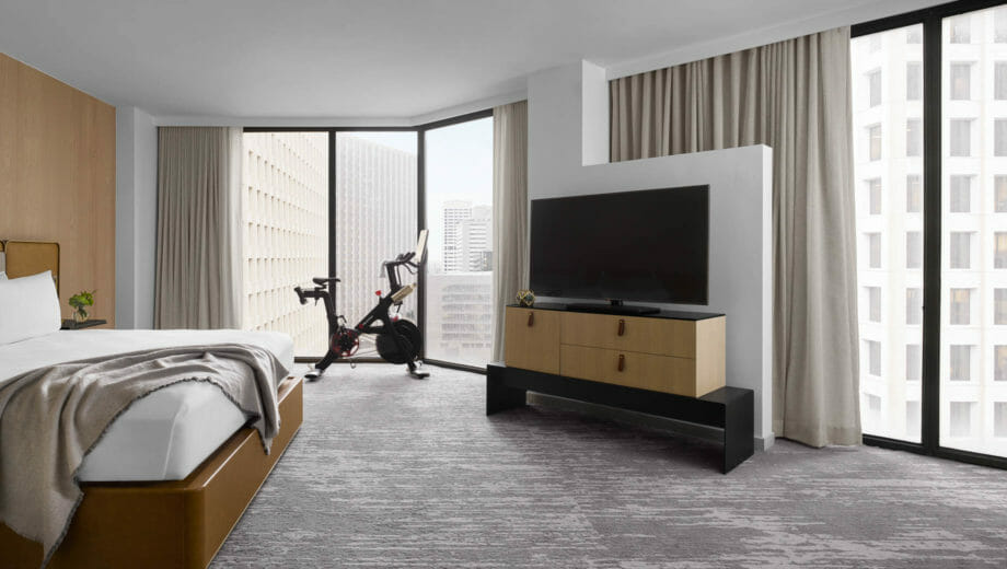 A king sized bed corner room with a TV and Peleton