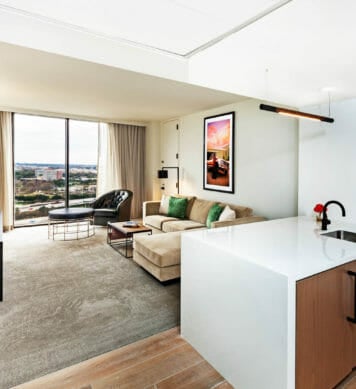 Living room in king suite that with kitchen counter, tan sectional, and entertainment center with flat screen tv