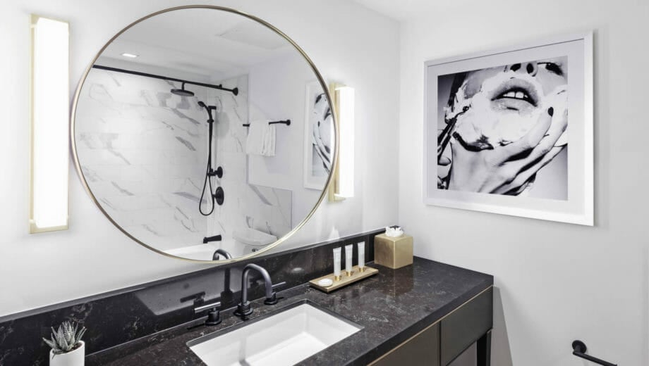 Circular mirror above bathroom sink with black counters