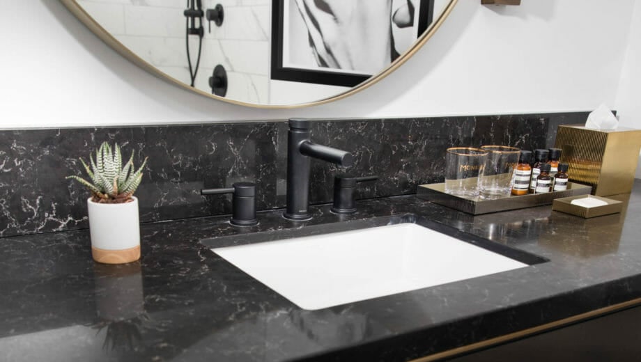 Circular mirror above bathroom sink with black counters