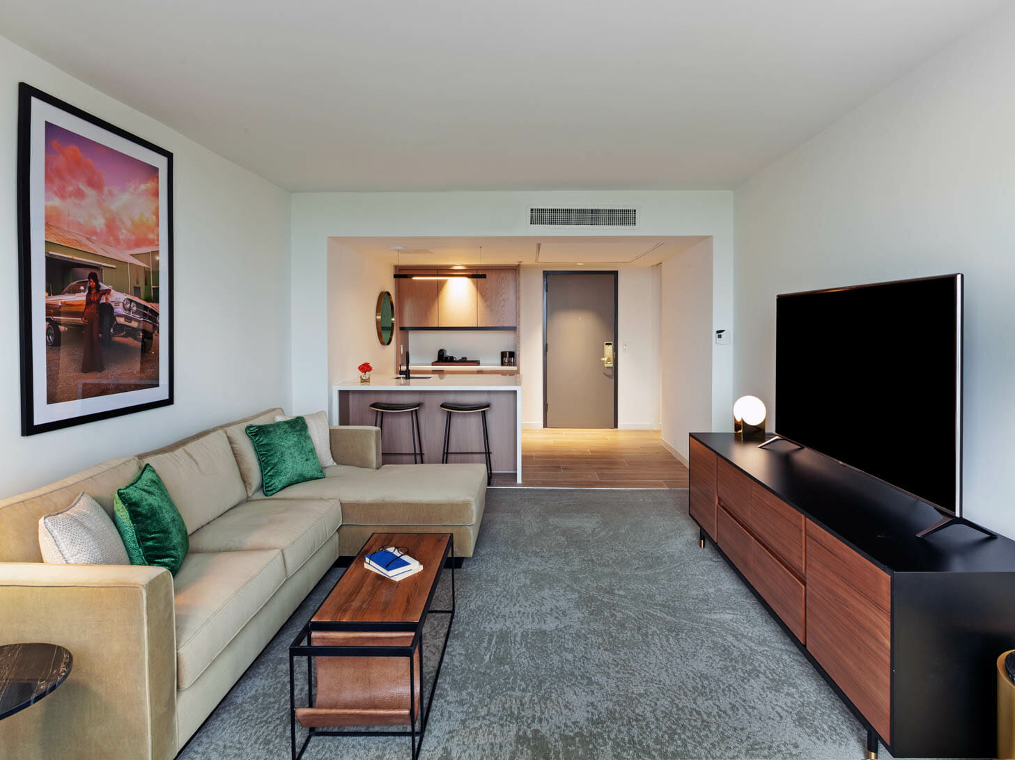 Spacious Presidential Suite living room with floor to ceiling windows, tan sectional in seating area and dining table behind it.