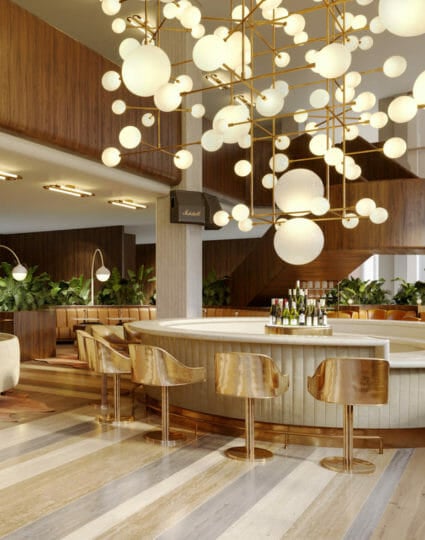Circular bar encircled with gold bar stools and has spherical ceiling lamps