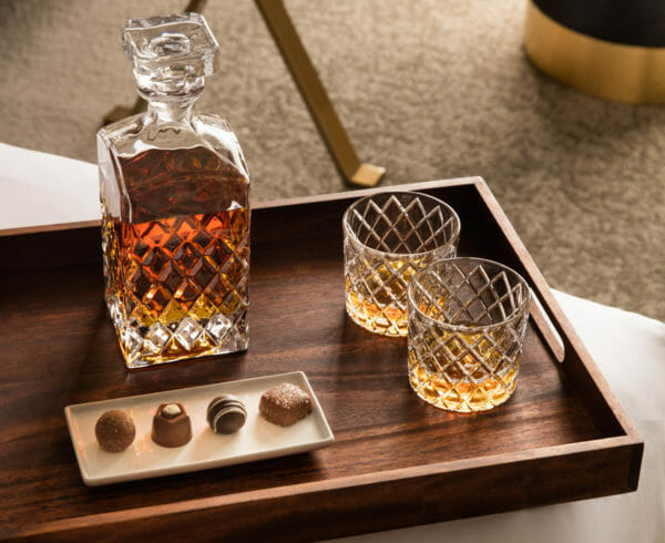 Whiskey decanter and glasses on bedside tray with chocolates