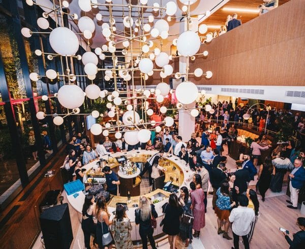 A large chandellier in a lobby with a circular bar below and people celebrating