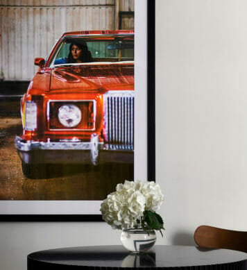 A close up of a dining room table with a picture of a woman in a red car on the wall
