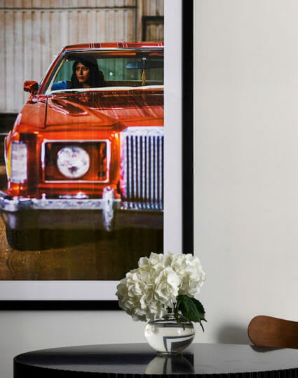 A close up of a dining room table with a picture of a woman in a red car on the wall