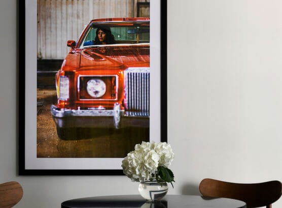 A close up of a dining room table with a picture of a woman in a red car on the wall