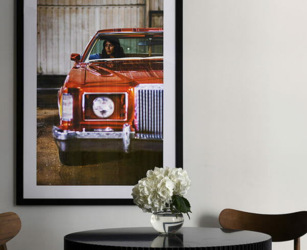 A close up of a dining room table with a picture of a woman in a red car on the wall