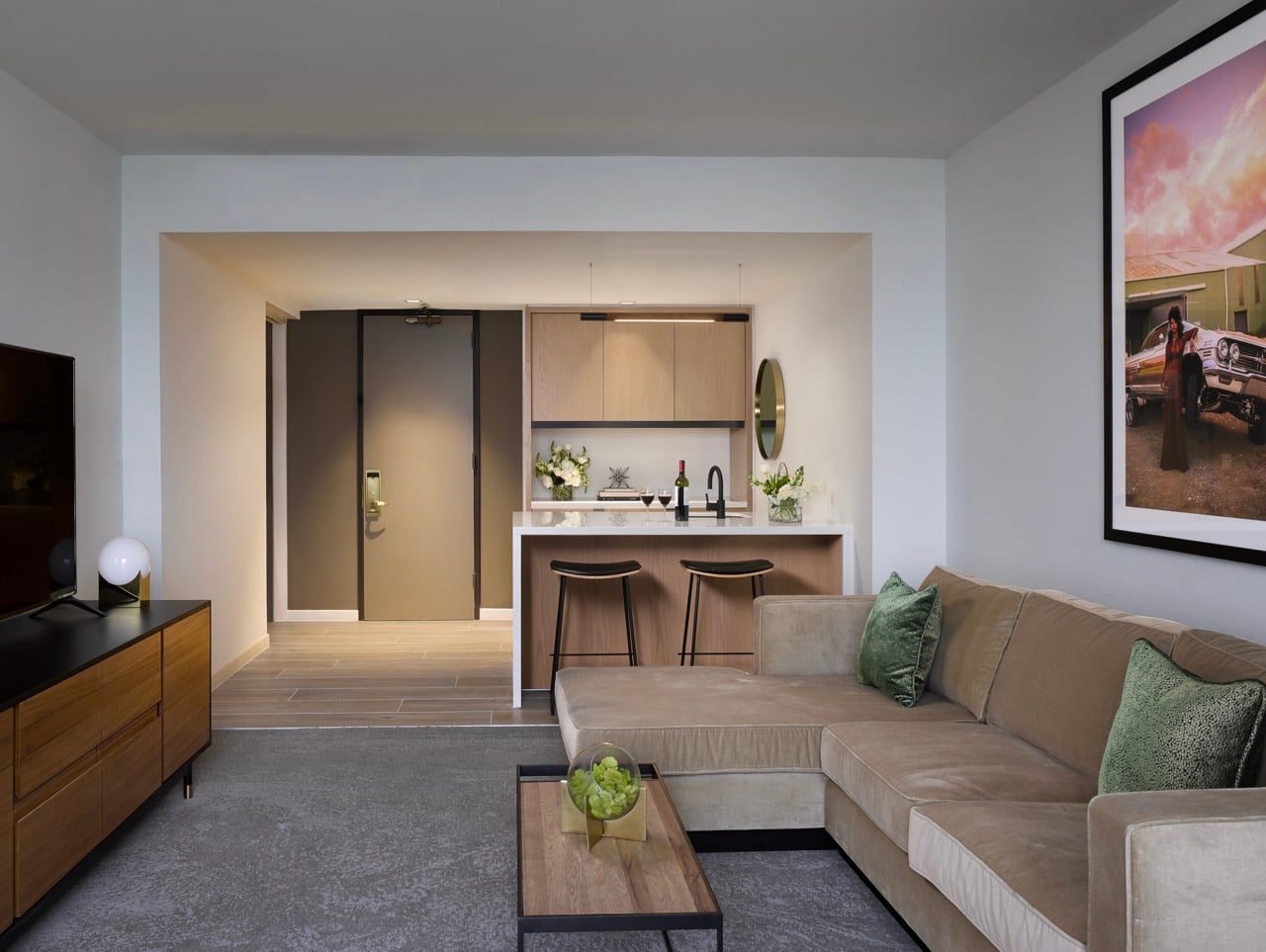 Spacious Presidential Suite living room with floor to ceiling windows, tan sectional in seating area and dining table behind it.