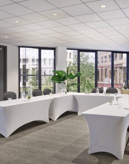 The I. Wilson meeting room at the C. Baldwin Hotel. The bright room has its tables set up in a U-shape for a professional event.
