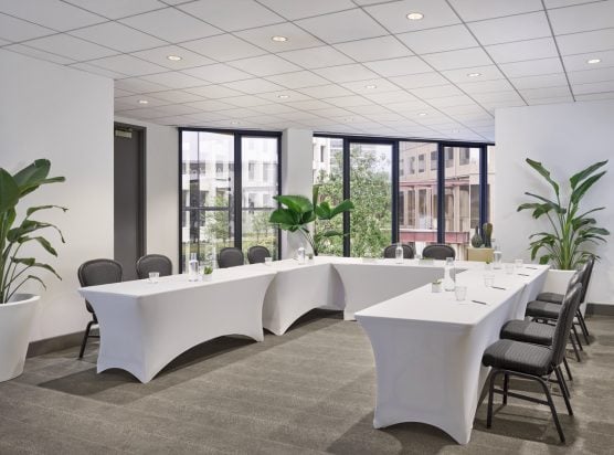 The I. Wilson meeting room at the C. Baldwin Hotel. The bright room has its tables set up in a U-shape for a professional event.